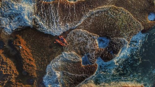 High angle view of women lying on shore at beach during sunset