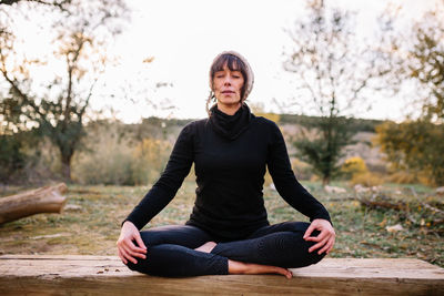 Woman practicing yoga and meditating on the park bench doing lotus position. 