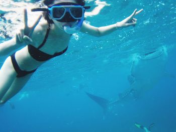 Woman showing peace signs while snorkeling in sea