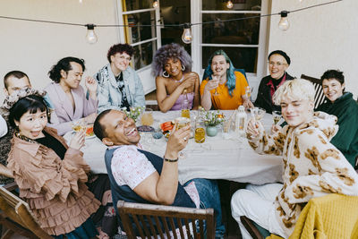 High angle view of friends from lgbtq community posing with drinks during dinner party in back yard