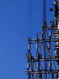 Low angle view of electricity pylon against clear blue sky