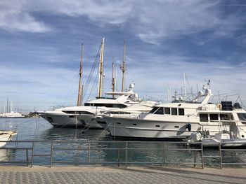 Sailboats moored at harbor against sky