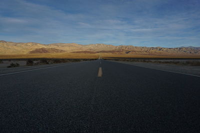 Road leading towards mountains against sky