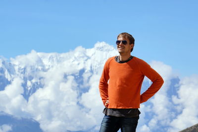 A young man stands smiling against the backdrop of the annapurna massif. upper mustang. nepal.