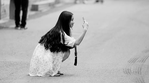 Side view of woman photographing on road