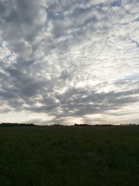 Scenic view of grassy field against cloudy sky