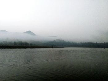 Scenic view of lake by field against sky during winter