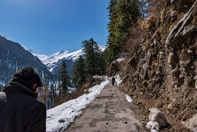 Rear view of people on mountain road during winter against sky