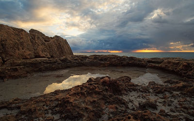 Rock formations in sea against sky during sunset