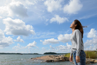 Woman standing by sea against sky