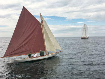 People sitting in sailboat on sea against sky