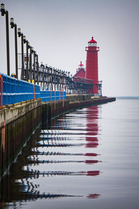 Lighthouse by lake against clear sky