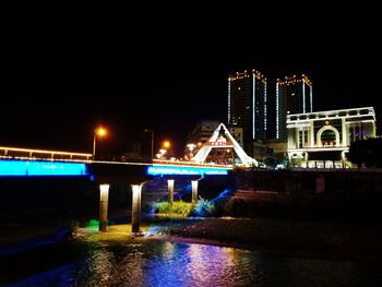 Illuminated bridge over river against sky at night