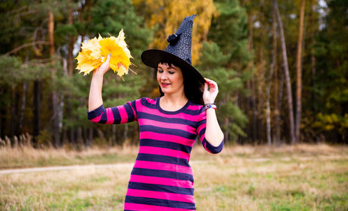 Witch throws leaves in the autumn forest. halloween costume party magician person