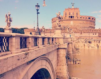 Arch bridge over river by historical building in city