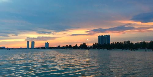 Sunset over calm sea with buildings in background