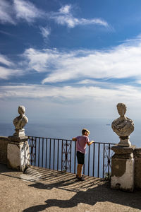 Statue standing by railing against sky