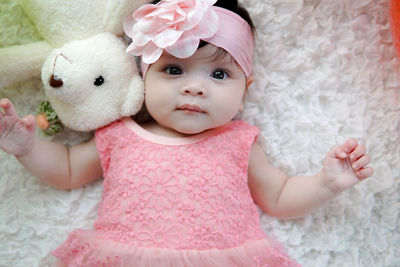 Close-up portrait of cute baby girl lying on bed at home