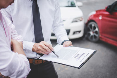 Midsection of agent discussing with client while standing on road