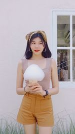 Portrait of a beautiful young woman standing against wall