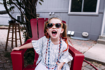 Portrait of girl shouting while sitting on chair