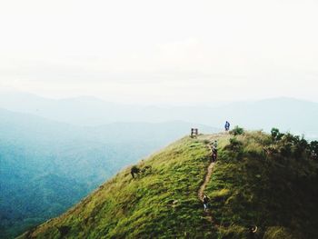 People on mountain peak against sky