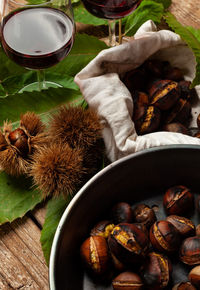 Top view of roasted chestnuts in iron skillet on wooden table.