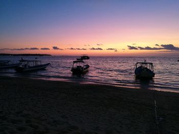 Boats moored at sea against sky during sunset