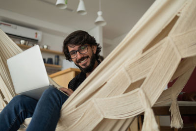 Young man  black glasses working with laptop on a white hammock notebook for working. home office