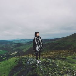 Smiling young woman standing on mountain against sky