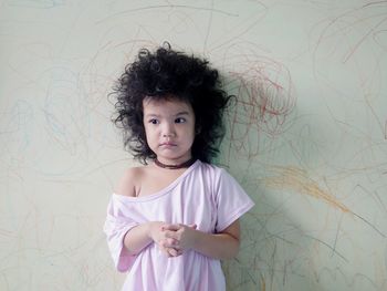 Portrait of cute girl standing against wall