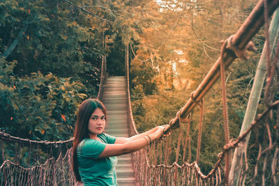 Full length of woman standing by railing in forest
