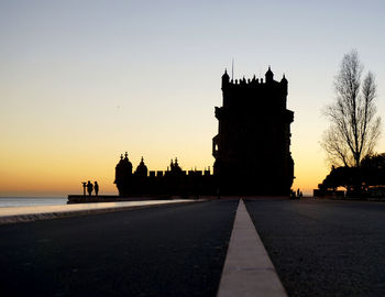 Road leading towards silhouette torre de belem during sunset in city