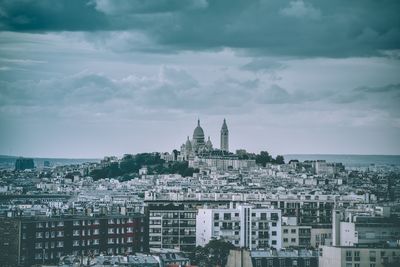 Buildings in city against cloudy sky