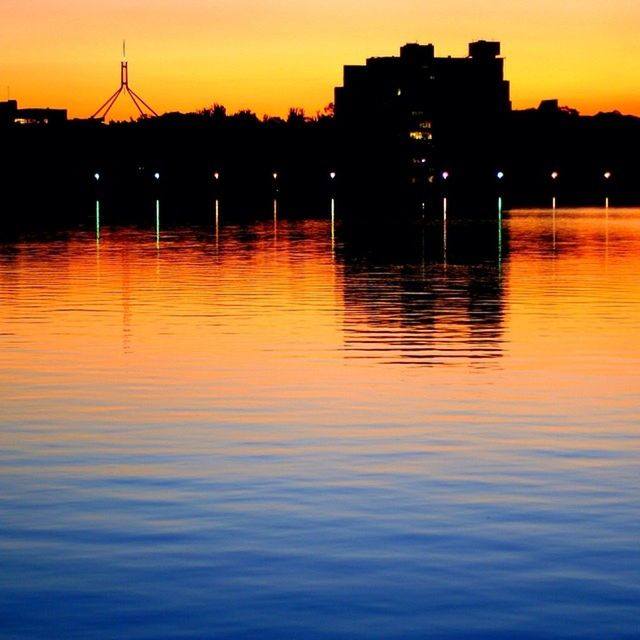 sunset, water, reflection, waterfront, building exterior, orange color, architecture, built structure, silhouette, illuminated, rippled, scenics, river, lake, tranquility, tranquil scene, sky, beauty in nature, city, idyllic