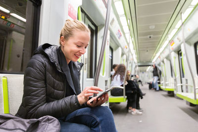 Smiling woman using digital tablet while sitting in train