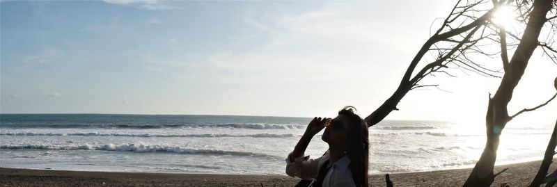 Panoramic view of woman at beach against sky