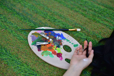 Cropped hand of woman by artist palette on lawn