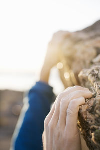 Cropped image of man climbing rock