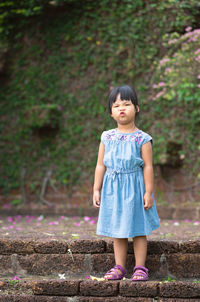 Full length portrait of cute girl puckering while standing on steps
