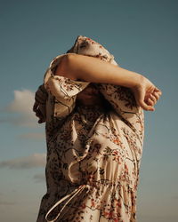 Midsection of woman holding umbrella standing against sky