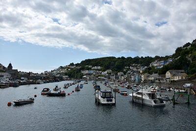 Boats moored in sea by townscape against sky