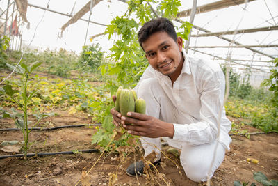 Portrait of smiling young man holding food in farm