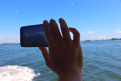 Midsection of man photographing sea against sky