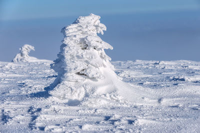 Snow covered land on field against sky