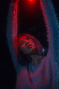 Portrait of young woman against black background