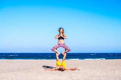 Couple exercising at beach on sunny day