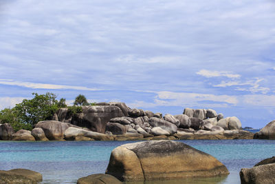 Scenic view of rocks by sea against sky