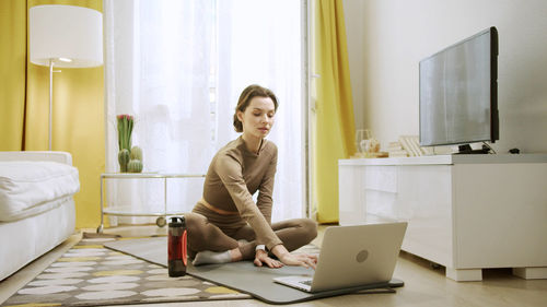 Full length of woman sitting on table at home