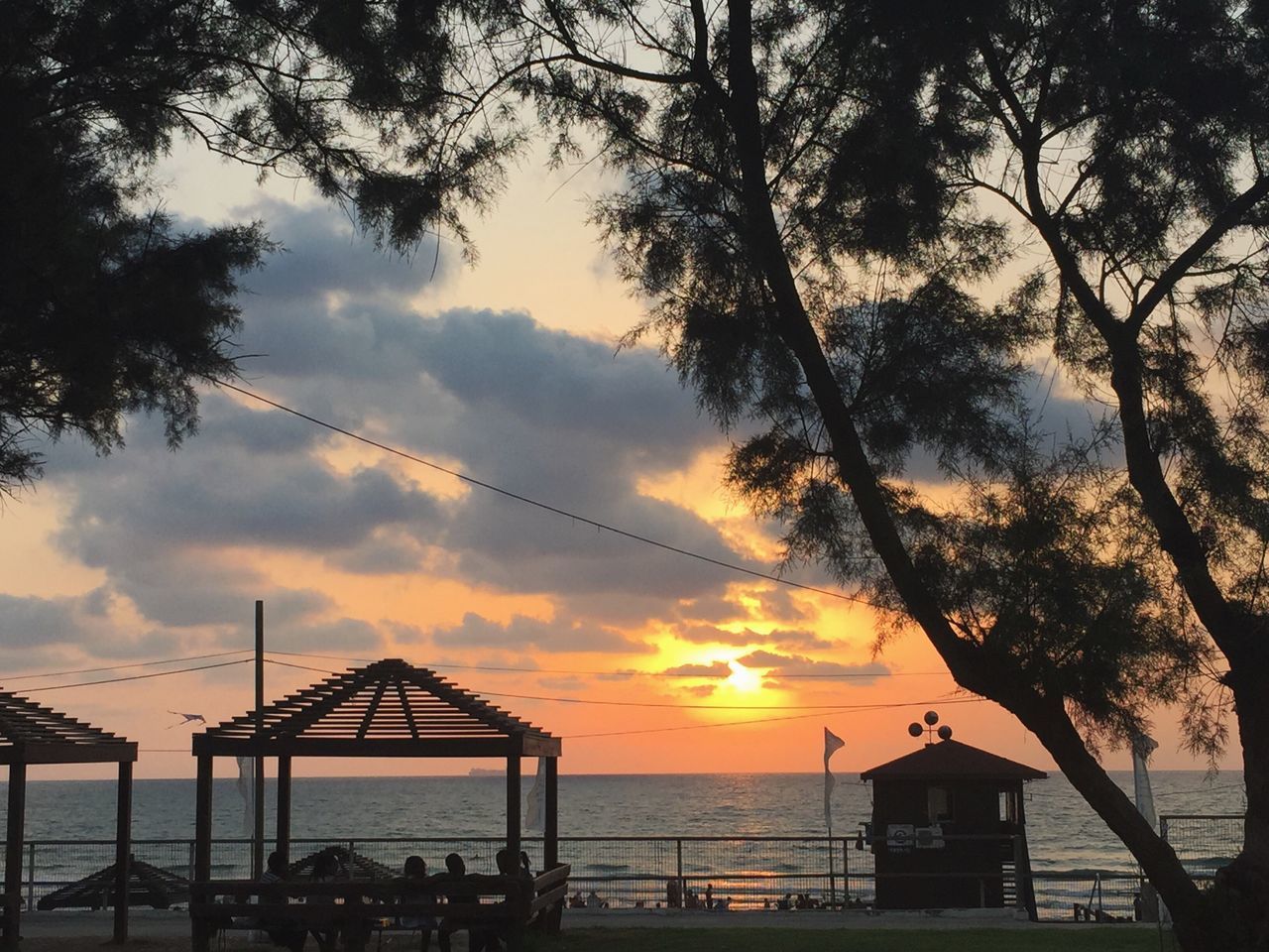 sunset, tree, beach, silhouette, sky, sea, water, vacations, tranquil scene, cloud, scenics, tourism, tranquility, cloud - sky, nature, beauty in nature, sun, branch, atmosphere, outdoors, solitude, distant, shore, majestic, remote, dramatic sky, ocean